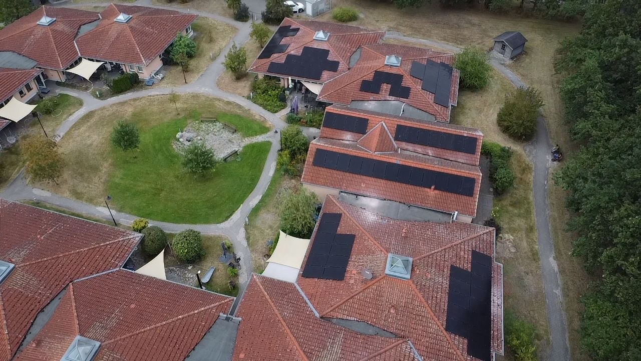 Luftaufnahme der Altenpflegehilfe in Hohen Neuendorf mit mehreren schwarzen Photovoltaikfeldern auf roten Ziegeldächern
