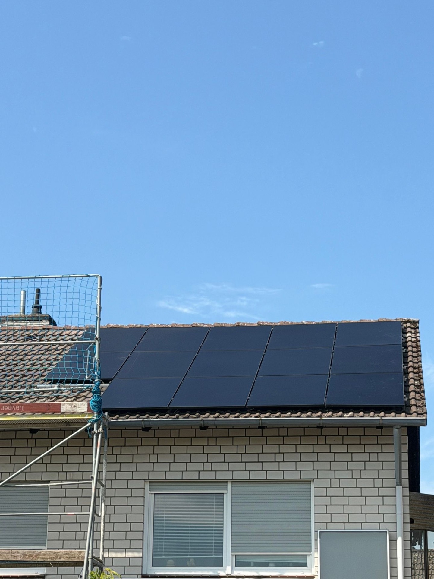 Fertiges Full-Black-Modulfeld auf dem Ziegeldach desselben Hauses